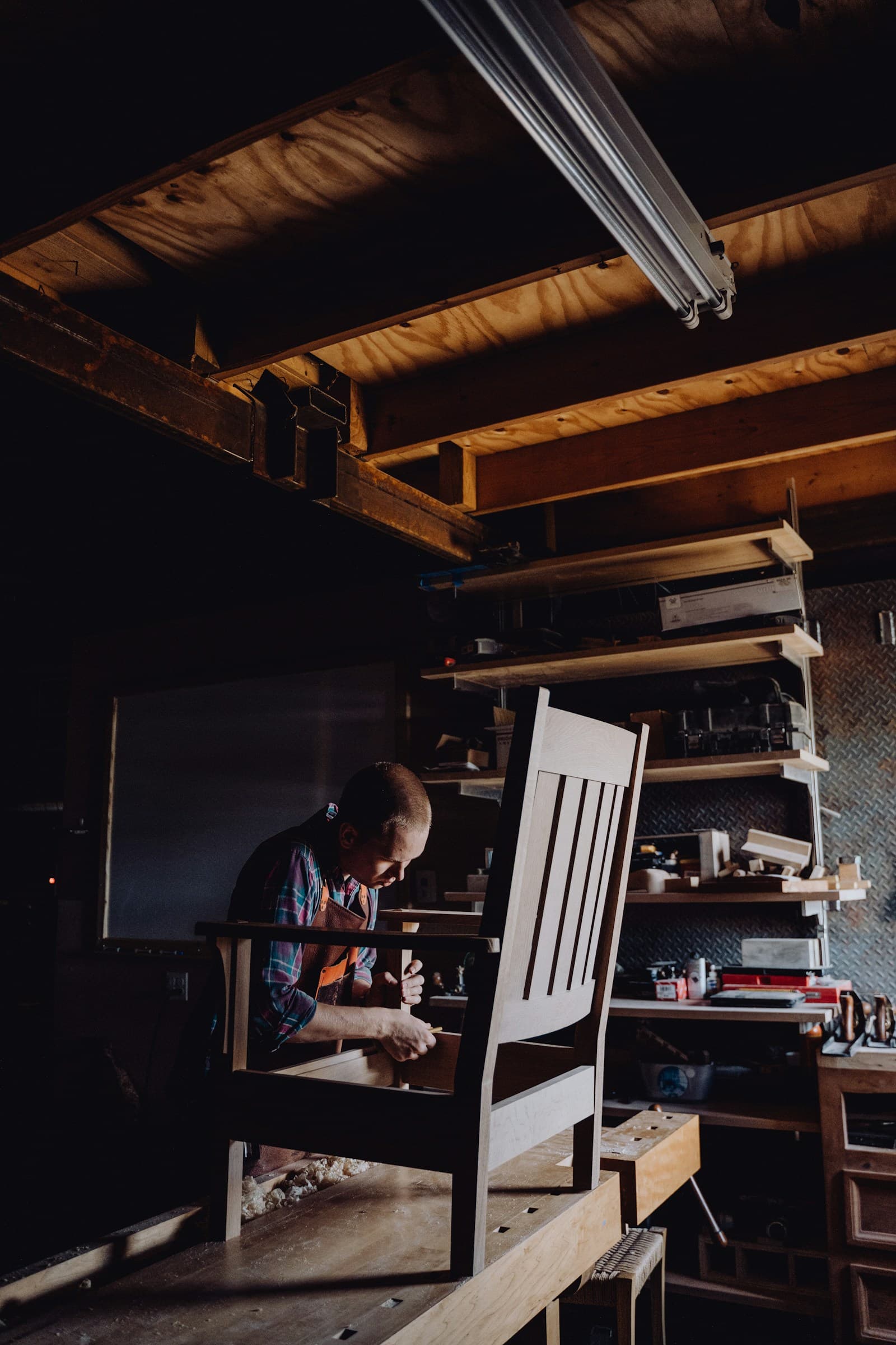 Jean Lefèvre, ébéniste, ponce une chaise en bois dans son atelier